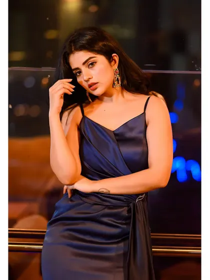 Pavithra Gowda striking a pose in the navy satin dress. The side drape is held in place with a subtle, sparkling clasp, adding a touch of detail to the minimalist design.