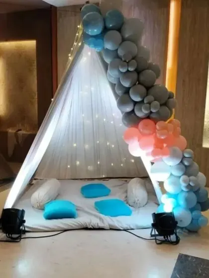 A simple and modern teepee tent decorated with a balloon garland in shades of blue and grey. This setup provides a stylish and comfortable nook for any small, private celebration.