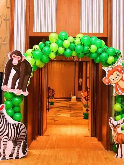 Guests were welcomed into the wild with this jungle-themed entrance arch. The green balloon arch is decorated with large, friendly animal cutouts like a monkey, zebra, and deer.