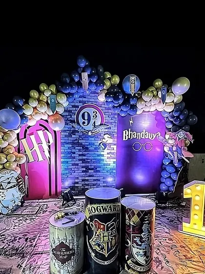 A magical Harry Potter themed birthday for a 10th birthday celebration. The decor features a Platform 9 3/4 backdrop, house crest props, and a balloon arch in house colors, all set up on a terrace for a nighttime event.