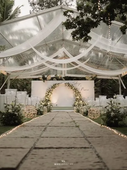 For this evening reception, we created a magical atmosphere with a transparent tent under the stars. The design focused on clean white florals, a stunning arched backdrop, and layers of romantic fairy lights, proving that minimalist decor can be incredibly impactful and breathtaking.