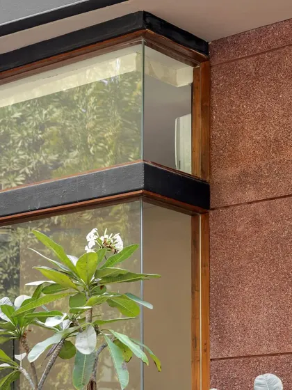 **Sanctum Site Office, Ahmedabad:** A detail shot of the corner window and textured red stone cladding. This close-up highlights our focus on material interplay and craftsmanship, even in a temporary structure like a site office.