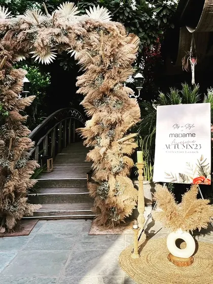 A beautiful boho-chic entrance arch made of pampas grass and dried palms, setting a stylish and earthy tone for a brand's autumn collection launch.