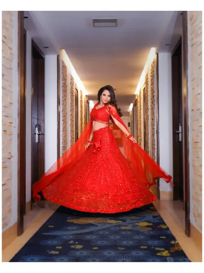 A joyful, twirling shot of the bride in her vibrant red engagement lehenga. The movement of the skirt and her happy expression create a dynamic and beautiful image.