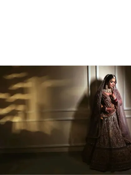 A moody and atmospheric bridal portrait. The dramatic lighting and shadows create a painterly effect, making the bride look like a character from a timeless story.