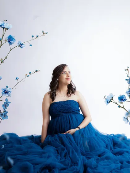 A beautiful portrait in shades of blue. The mom-to-be is seated amidst a sea of blue tulle, with floral branches adding an artistic touch.