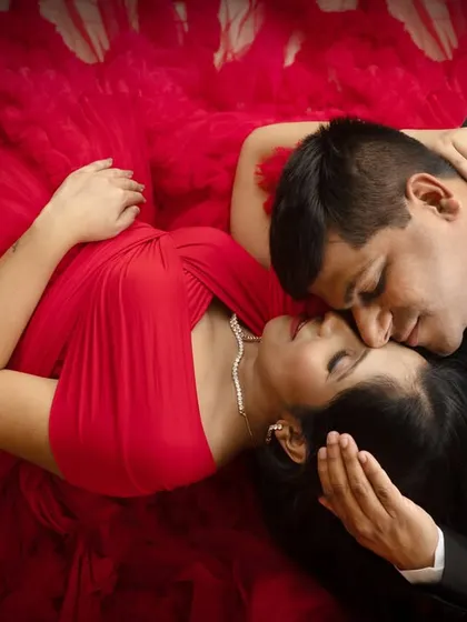 An intimate top-down view of a couple, captured in a moment of closeness. The vibrant red fabric creates a passionate and dramatic frame.