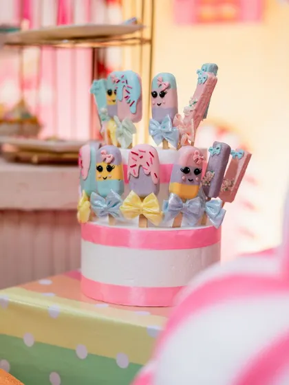 Adorable cakesicles decorated to look like cartoon ice cream bars with little bows. These small details make the dessert table extra special.