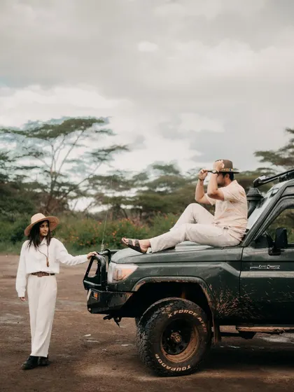 A stylish, adventurous portrait of Nikita and Harshil with their safari vehicle. This shot has an editorial feel, like a still from a classic adventure movie.