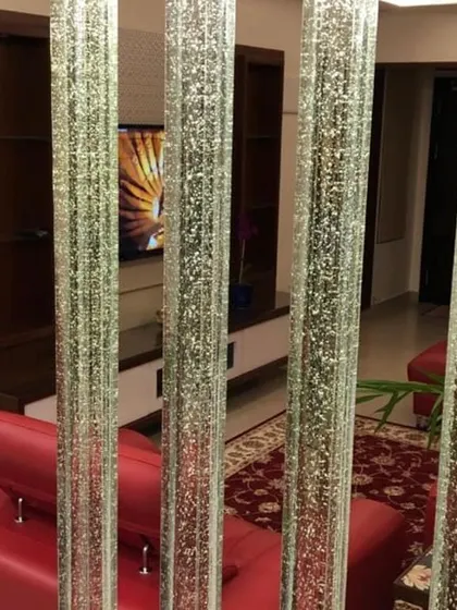 A close-up of a creative room divider made of vertical glass bubble rods. This partition separates spaces while maintaining an open feel, adding a decorative and light-filled element to the living area.