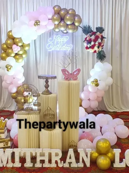 A simple and elegant ring decoration with pink, white, and gold balloons against a white curtain backdrop.