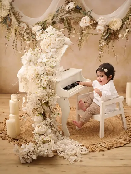 Our studio is filled with unique props like this miniature white piano, allowing us to create elegant and artistic portraits that highlight your baby's curious nature.
