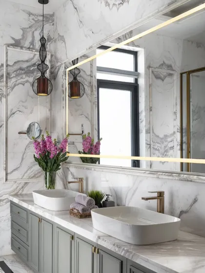 Luxury lies in the details. In this master bathroom, we paired dramatic book-matched Italian marble with a custom sage green vanity and brushed gold fixtures. The result is a serene and sophisticated sanctuary, proving that functional spaces can also be exceptionally beautiful.