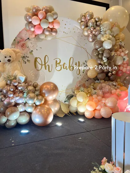 A closer look at the elegant "Oh Baby" baby shower decor, highlighting the beautiful floral-printed backdrop and the intricate arrangement of rose gold, beige, and pink balloons.