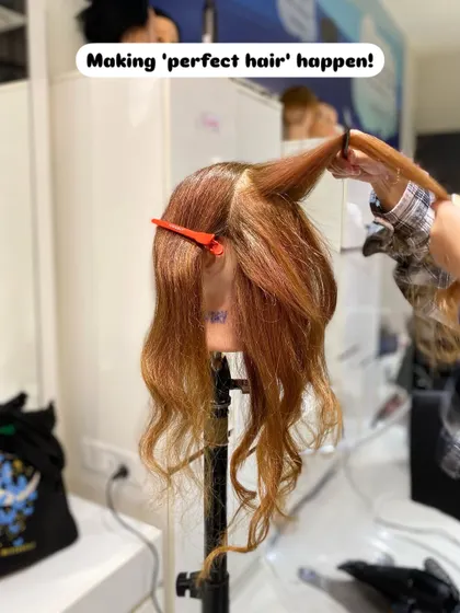The process of creating perfect curls. A student sections and styles hair on a mannequin, practicing the techniques taught in our hairstyling program.