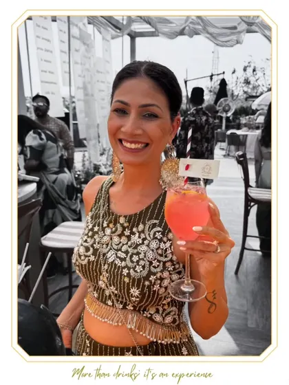 A guest looking radiant with her pink cocktail at a beautiful brunch event. Our drinks are designed to complement the style and atmosphere of any celebration.