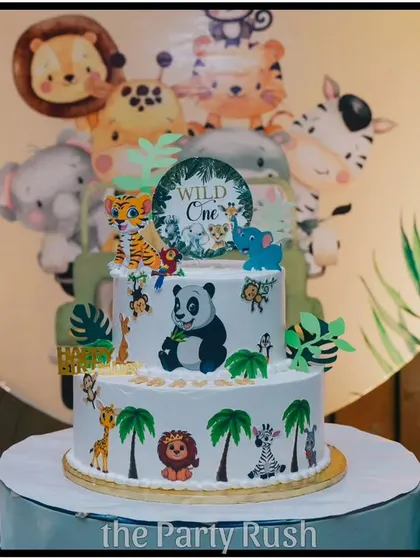 A close-up of the beautifully decorated two-tier cake for Aaryan's "Wild One" party. The cake is adorned with edible jungle animals and sits perfectly within the overall safari theme.