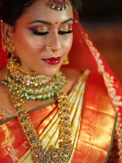 A close-up on this bride's classic look. The combination of glittery gold eyeshadow and a glossy red lip is perfect for a festive Muhurtham ceremony.
