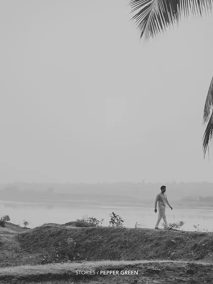 An atmospheric, black and white shot of the groom walking near the serene backwaters. This kind of scene-setting shot adds a cinematic quality to the wedding film.