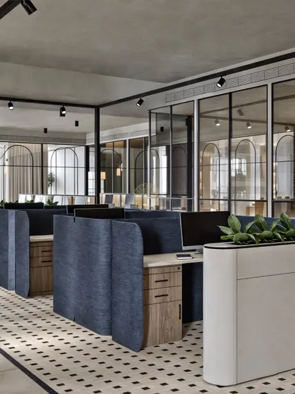 Here, we used curved, fabric-covered partitions in a deep blue to define individual workstations. This adds a pop of color and a soft, acoustic element to the open office, complemented by the geometric black and white flooring.