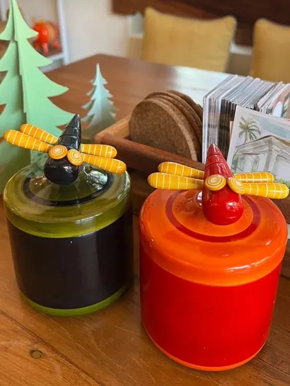 Our dragonfly dabbas, seen here on a festive table, are perfect for storing small items. Their vibrant colours and whimsical design, handcrafted in Channapatna, bring a playful energy to your home.