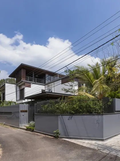 Exterior views of the Mango Tree Yard home, highlighting its contemporary form, clean lines, and the use of screens for privacy and ventilation.