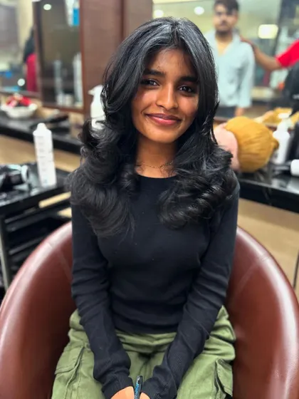 A happy client showcasing her new advanced layer haircut with a face-framing fringe. The style is finished with a perfect blow-dry that adds volume and enhances the layers.