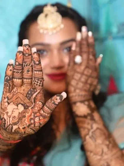 A close-up of a bride's hand, showing a beautiful Ganesha motif on the palm. This is a popular choice for bringing blessings and good fortune.