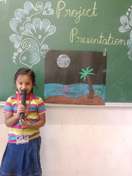 A student presents her beautiful artwork depicting a night scene, showcasing her artistic talent and presentation skills.