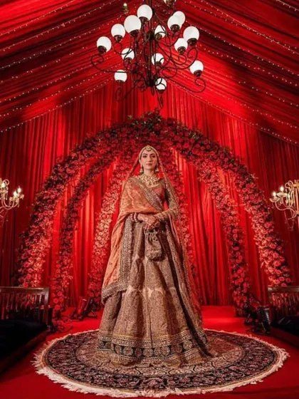 A breathtaking bridal portrait within a royal red themed decor, featuring dramatic draping and a grand floral arch.