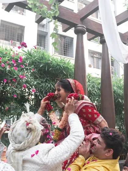 The bride being lifted by her family during the varmala ceremony, a fun and traditional moment of friendly competition.