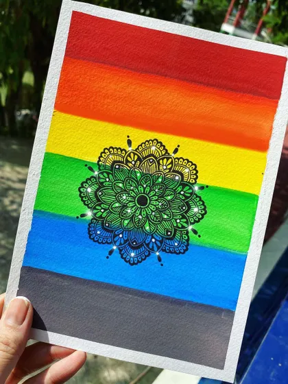 A mandala drawn over a vibrant rainbow watercolor background, created for Pride Month. This shows how you can combine different mediums to make your mandala art even more expressive.
