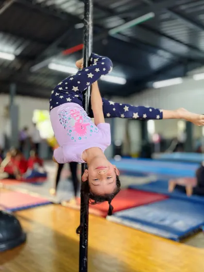 This is what a super girl looks like. Hanging upside down with a smile, she makes this challenging pole move look easy, inspiring everyone around her.