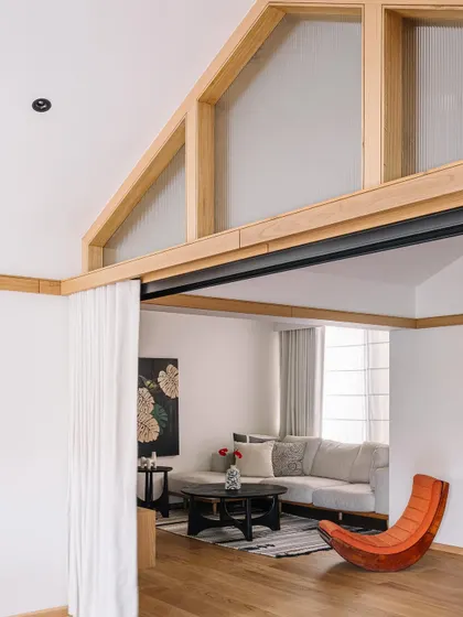 **Cocoon House, Ahmedabad:** A view into a cozy seating nook, separated by a simple curtain. The design uses internal windows and partitions to create distinct zones without sacrificing the open, airy feel of the home, offering both privacy and connection.