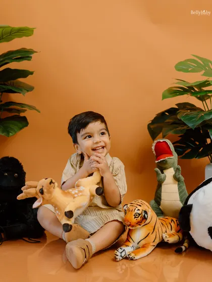 A candid moment of joy during the jungle adventure shoot. The warm orange backdrop and lush plants create a perfect wild atmosphere.