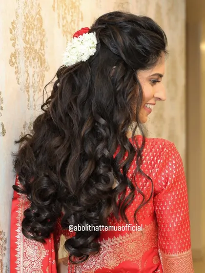 A back view of a beautiful half-up, half-down hairstyle with voluminous curls. This is a great option for engagement or reception looks.