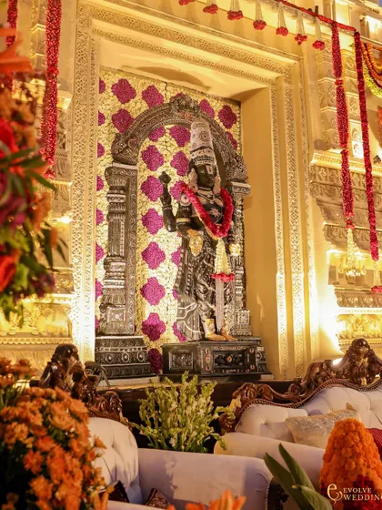 The deity of Lord Venkateswara, intricately detailed and set against a backdrop of purple and gold floral patterns. This element was central to creating a sanctum of devotion within the wedding space.
