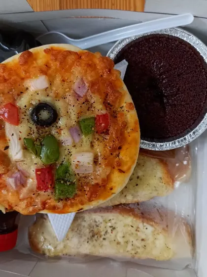 Mini pizza, garlic bread and chocolate cake sit together in one of our individual party snack boxes.