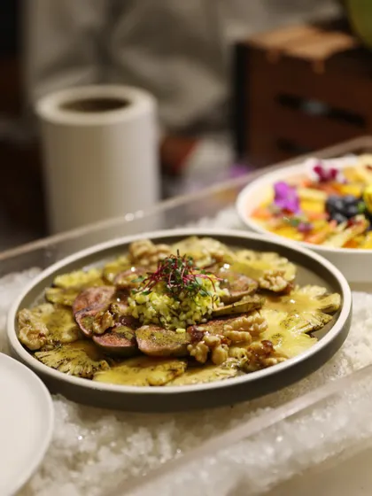 A platter of thinly sliced pineapple carpaccio, served on a bed of ice. This unique and refreshing dish showcases our creative approach to fruit and salad preparations.
