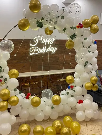 An elegant white and gold balloon backdrop. The square frame is adorned with white balloons, gold chrome accents, and clear confetti balloons for a touch of sparkle.