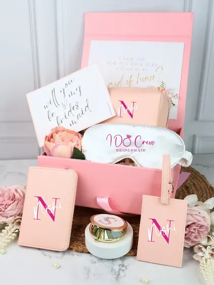 This personalized bridesmaid hamper in a soft pink theme is perfect for asking "Will you be my bridesmaid?". It features a custom eye mask, a monogrammed passport cover and luggage tag, and a beautiful pocket mirror.