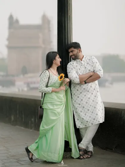 A stylish pose by a lamppost, with the Mumbai harbor as the backdrop. This shot has a classic, timeless feel.
