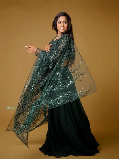 The movement of the sheer, sequined dupatta creates a beautiful, flowing shape. This studio shot against a simple background puts all the focus on the elegant green lehenga.