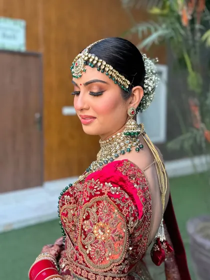A side profile of this scarlet and metallic gold bridal look, showcasing the intricate hair and the flawless, glowing skin.
