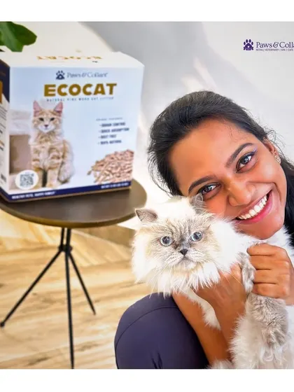 A happy pet parent cuddles her cat next to a box of EcoCat litter. This image captures the satisfaction of finding a sustainable, high-quality product that works for both pet and owner.