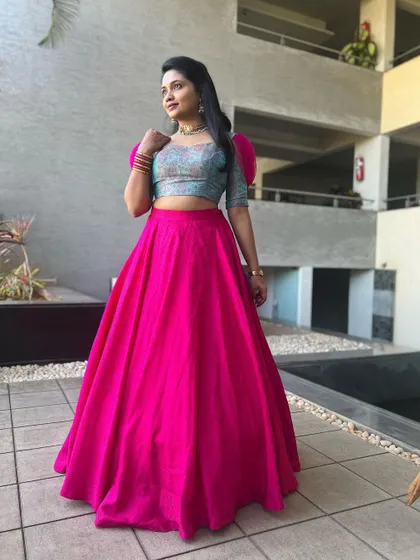 A full-length shot of the model in the bright pink and blue lehenga, a fun and modern choice for a festive party.