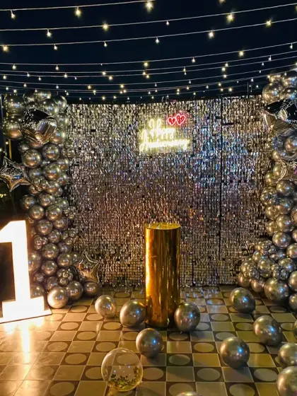 A beautiful terrace setup for a first anniversary. I used a silver shimmer wall, marquee lights for the number '1', and lots of silver balloons to create a magical, open-air celebration space.