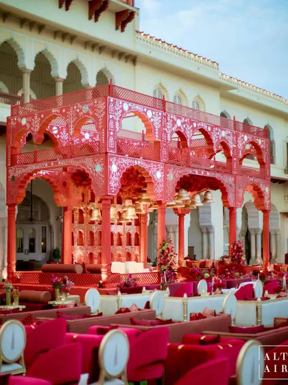 A daytime view of the 'Kaanch Bagh' mandap, showing the intricate red and white structure. This two-tiered design, inspired by royal architecture, created a stunning focal point for the wedding ceremony.