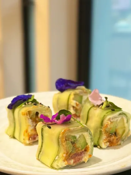A light and refreshing appetiser. These rolls are wrapped in thin slices of zucchini instead of seaweed, filled with seasoned rice and vegetables, and garnished with edible flowers for a beautiful finish.