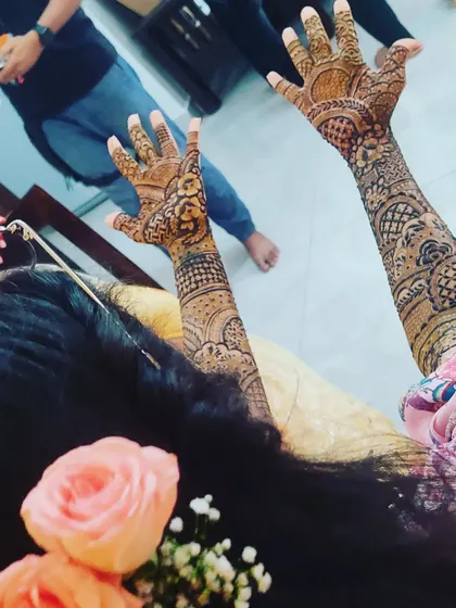 A candid shot from a mehendi session, with the bride joyfully showing off her freshly applied henna.